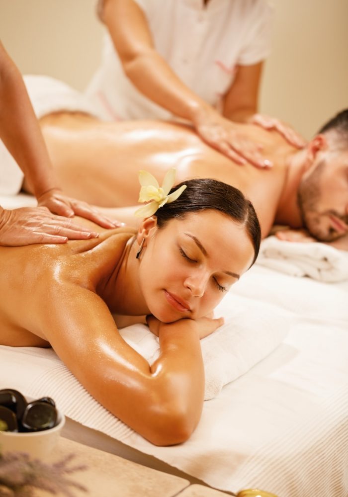 Young couple relaxing during back massage at health spa. Focus is on young woman.