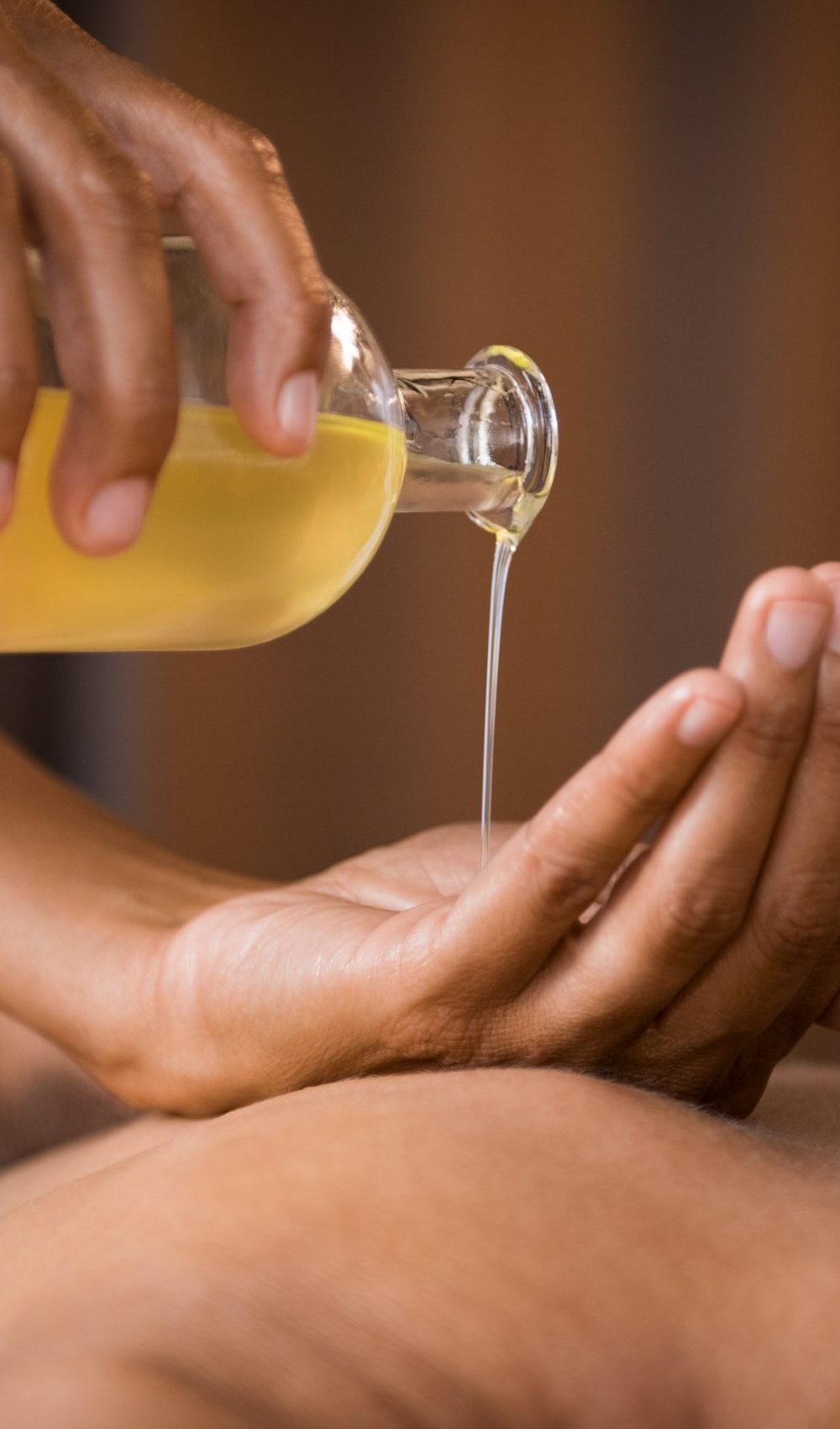 Closeup of masseur hands pouring aroma oil on woman back. Masseuse prepare to do oriental spa procedure for relaxing treatment. Therapist doing aromatherapy oil massage on woman body.
